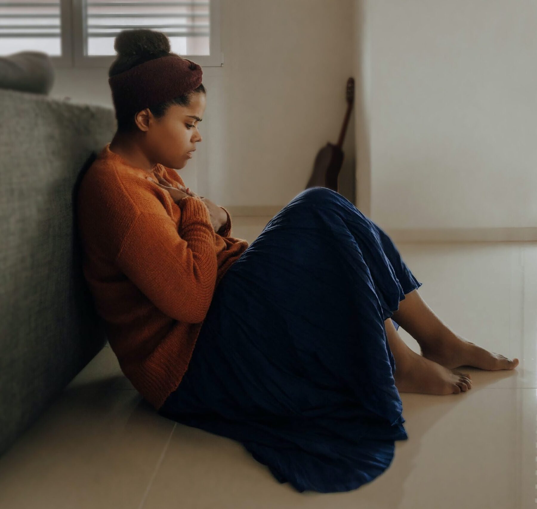 girl sat on floor with hand on chest