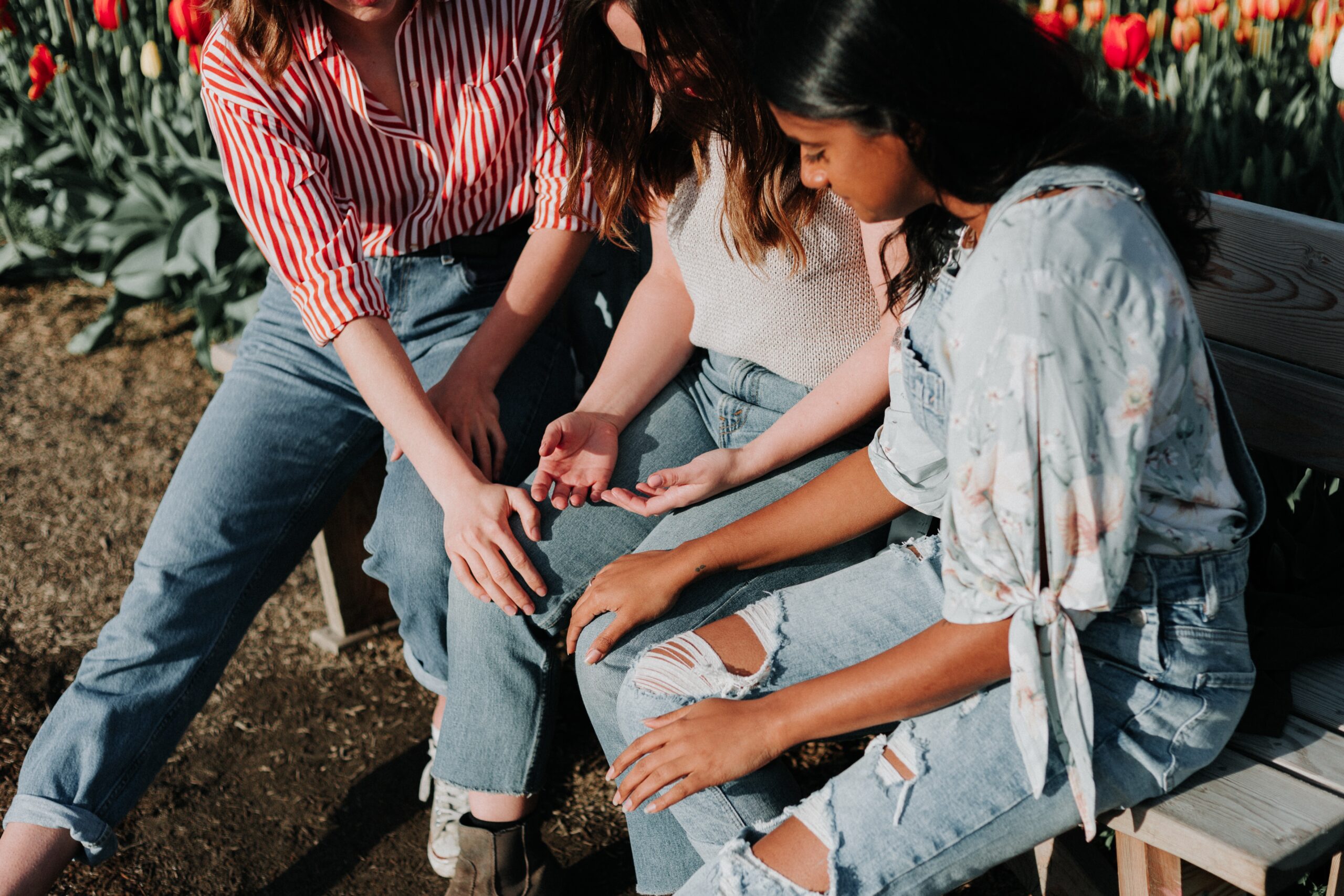Two young people sat on a bench supporting their friend